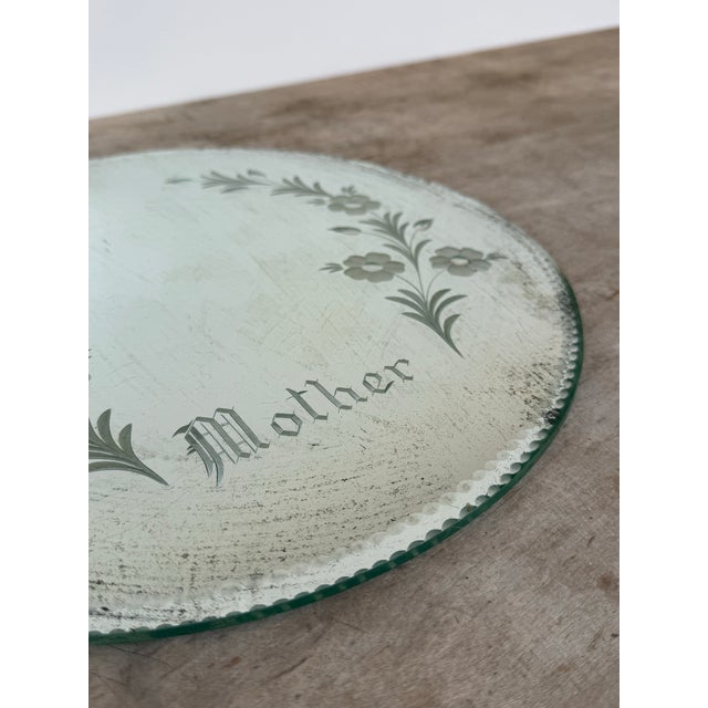This is a lovely vintage glass mirror etched with flowers and “Mother” at the center bottom. Pie crust edge and green felt...