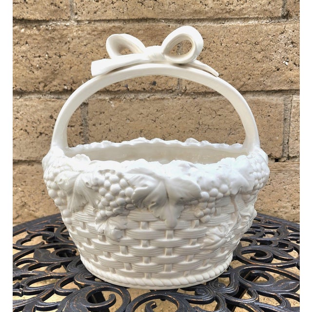 A vintage Italian Blanc De Chine ceramic basket with a decorative basket weave pattern. Grapes and leaves surround the top...