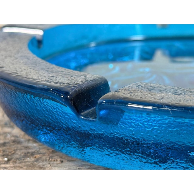 Vintage mid century art glass ashtray in a rich deep blue tone featuring a molded swirl pattern to the base and four...