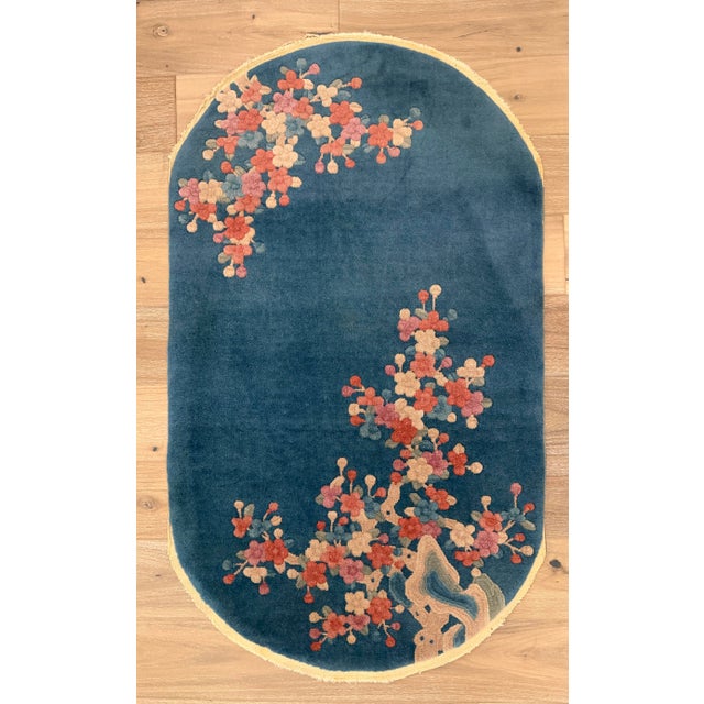 Hand-knotted wool rug measuring 2'7" x 4'5" (31" x 53"), featuring an oval shape with an open teal-blue field and...