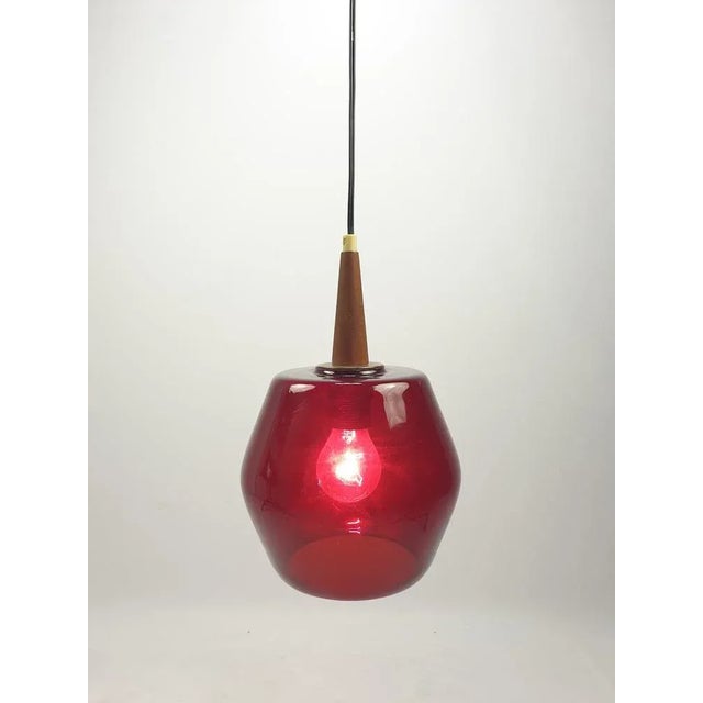 Very nice pendant fabricated in The Netherlands in the 70's. Beautiful red colored glass lampshade with a teak holder....