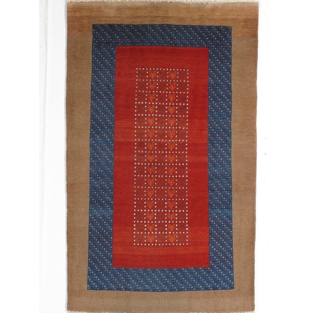 Hand-knotted Persian Gabbeh wool rug with a vibrant red field decorated with a geometric lattice of small stylized plant...