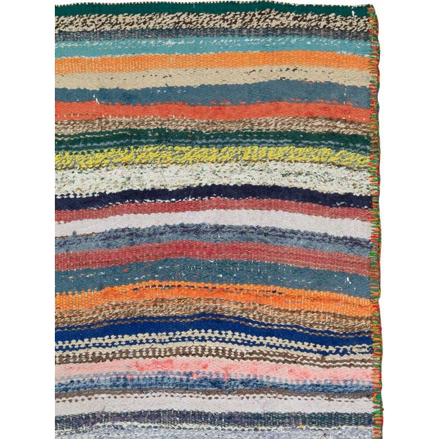 This Mid-20th century Persian flatweave kilim showcases a lively yet harmonious field of horizontally banded stripes...