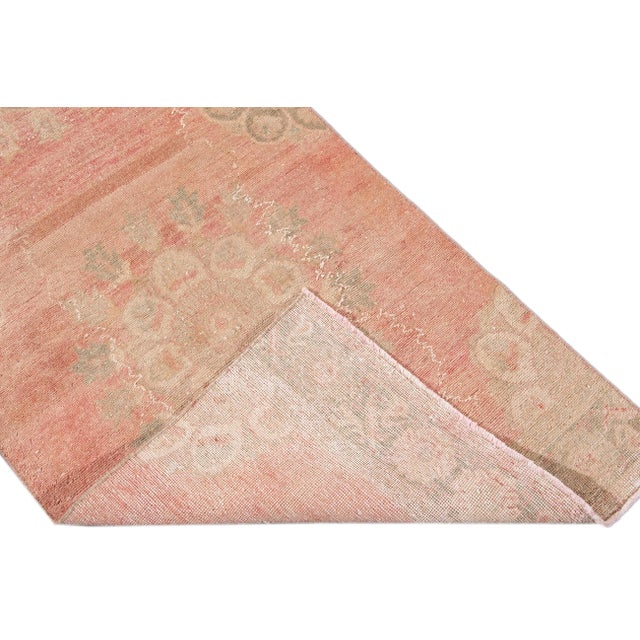 Beautiful vintage Turkish hand-knotted wool rug with a pink-rose field. This rug has a tan, ivory, and blue accents in a...