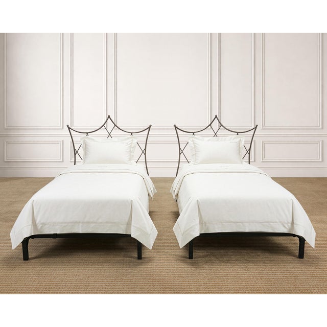 A dramatic pair of mid-century twin sized patinated iron bed frames crafted in a whimsical French Neoclassical style. The...