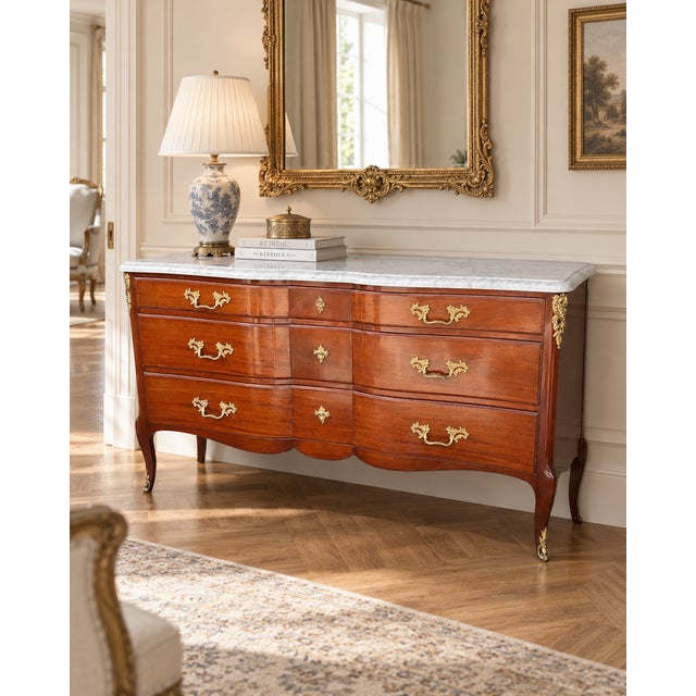 A substantial French Louis XV-style triple commode featuring a beautifully shaped serpentine front, warm figured wood, and...
