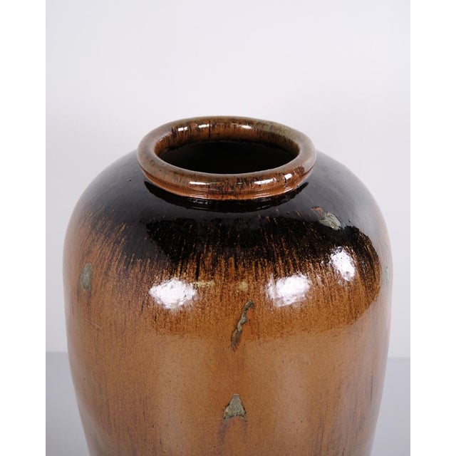 Large floor vase made in ceramic with a brown glaze. The vase has a simple design and large size, making it suitable as a...