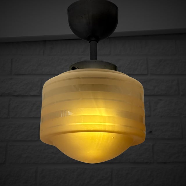 A Scandinavian modernist pendant lamp produced in the 1930s. The fixture is crafted from brushed steel and fitted with a...