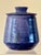A stoneware lidded jar in Periwinkle glaze. Bluish purple swaths of color decorate the surface. Inscribed on underside...