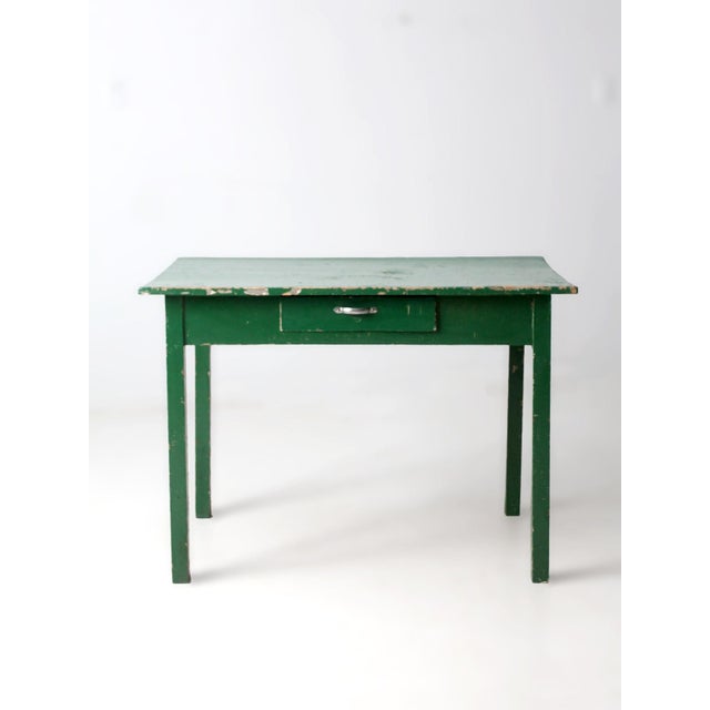 Early 20th century American farmhouse table finished in a deep heritage green with a single center drawer and strong,...