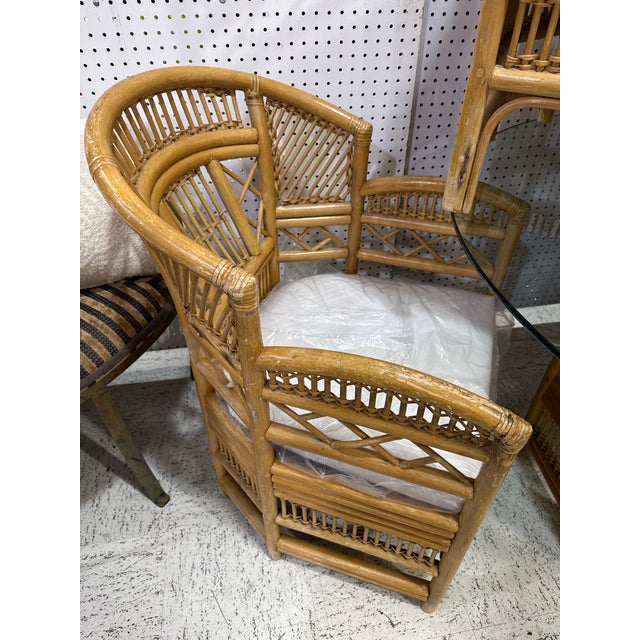 A charming vintage Brighton Pavilion-style rattan dining set featuring a round glass-top table and four coordinating...