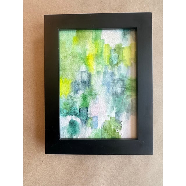 A serene and atmospheric original watercolor featuring layered washes of soft greens, blues, and hints of pink. This piece...