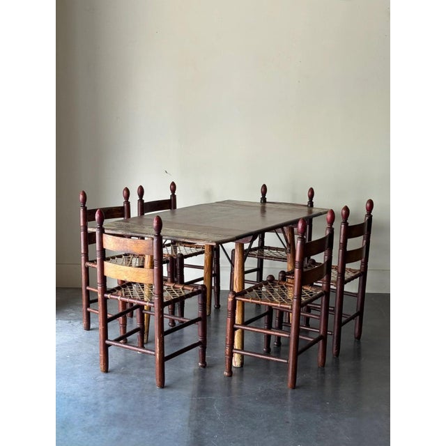 Incredible antique dining set with painted wood table and painted ladder back chairs with catgut seats. The set includes a...