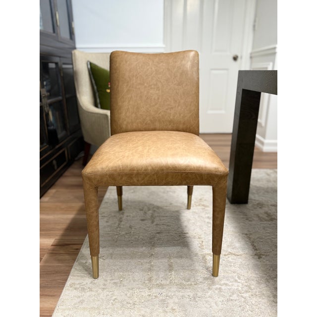 Perfect for modern dining, this armless chair features sleek lines covered in a rich camel faux leather accented with...