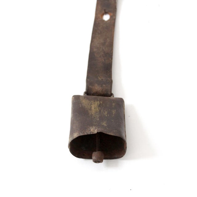This antique cow bell features a wide leather strap and shows remnants of its original gold finish on the bell. The...