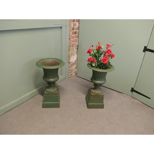 A Pair of Cast Iron Urns, Garden Planters These are very attractive urns they are made in cast iron and standing on...
