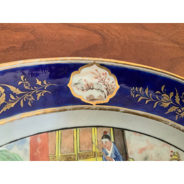 Solid blue border with gilt detailing with cartouches depicting landscapes. This porcelain serving platter has central...