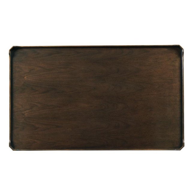 A rectangular top with chamfered corners is placed over four tapering legs that are joined by a low shelf. The table is...