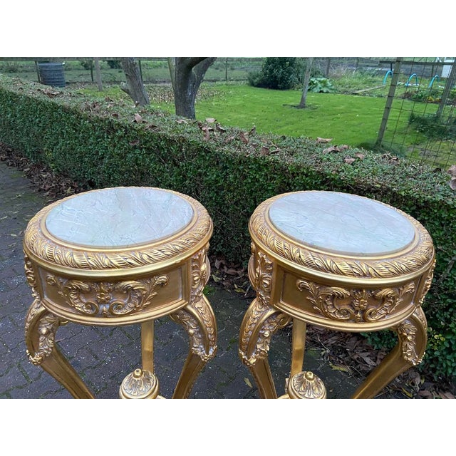 This elegant matching pair of late 20th-century French Louis XVI–style pedestal side tables combines sculptural giltwood...