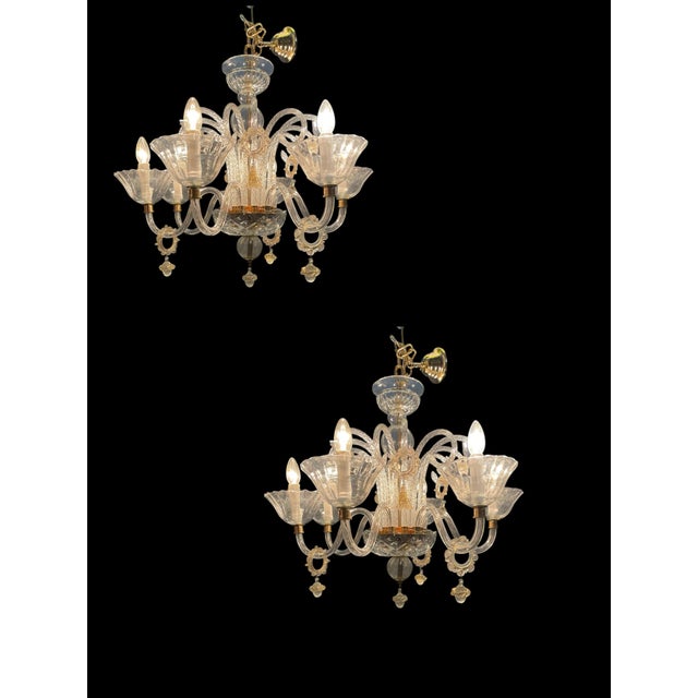Elegant pair of Italian Murano glass chandeliers from the 1970s, crafted in transparent glass with refined gold accents....