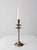 A vintage brass candlestick holder featuring a tall, tapered form, an intricately etched floral base, and double drip...