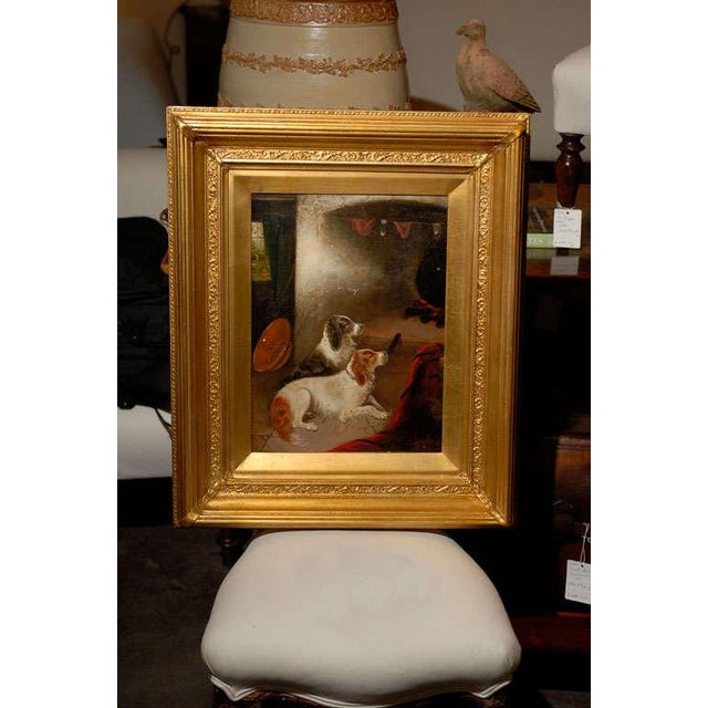 This 19th century oil painting, framed in a rectangular giltwood molded and carved frame, depicts two reclining spaniels...