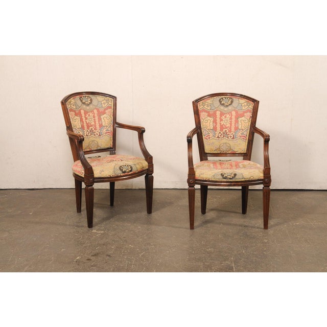 An Italian pair of Neoclassical style carved wood and upholstered armchairs from the mid-20th century. These mid-century...
