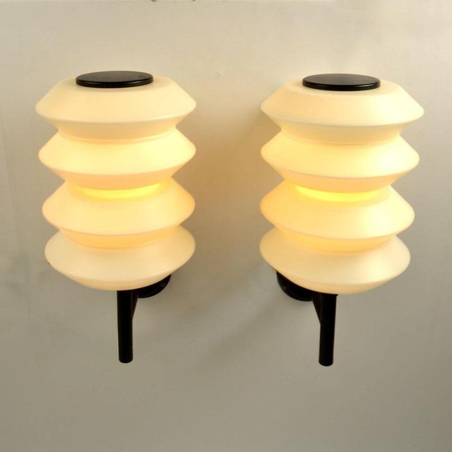 Rare large outdoor lanterns, wall lamps opaline glass shades hold by a black metal frame, by Raak, Holland circa 1968. The...