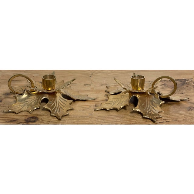 Vintage pair of brass poinsettia motif candle holders with a finger loop. Each holds a single taper candlestick. Festive...