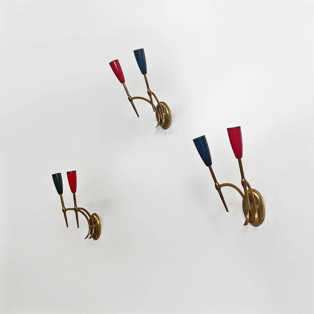 Italian mid-century modern two-arm brass wall lamps with cone lamp holder, 1950s. Set of three wall lamps or sconces with...