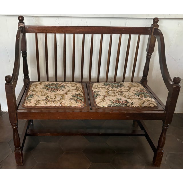 This lovely spindle back wooden bench has curved arms, turned legs, and floral tapestry style upholstered seats. As...