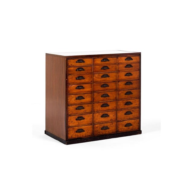 A proud bank of pitch pine and oak haberdashery cabinet with an arrangement of twenty four smooth running drawers. Each of...