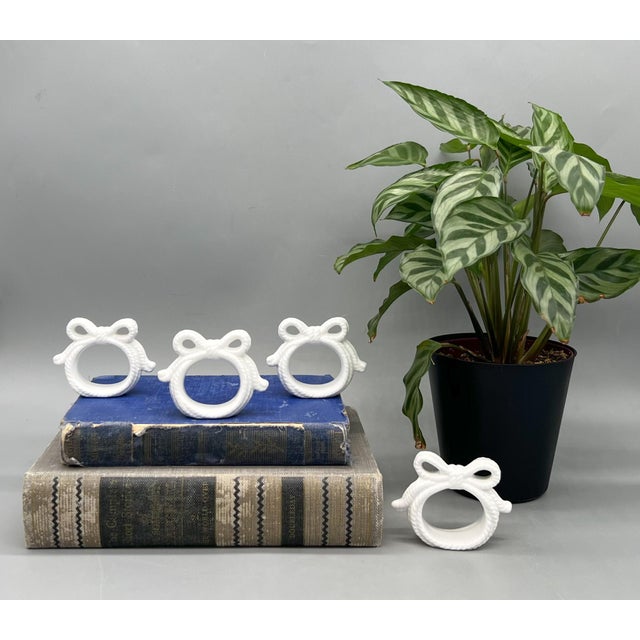Charming set of four vintage ceramic napkin rings with a classic rope-and-bow motif in crisp white glaze. The sculpted...