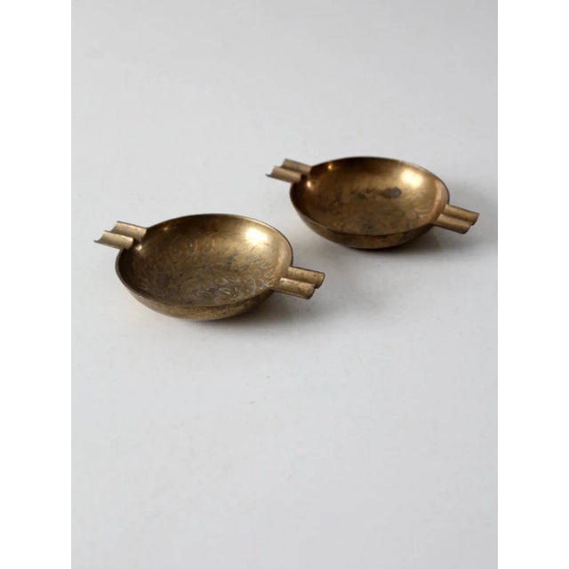 This pair of vintage brass ashtrays showcases a timeless floral motif in a classic round form. Each dish features dual...