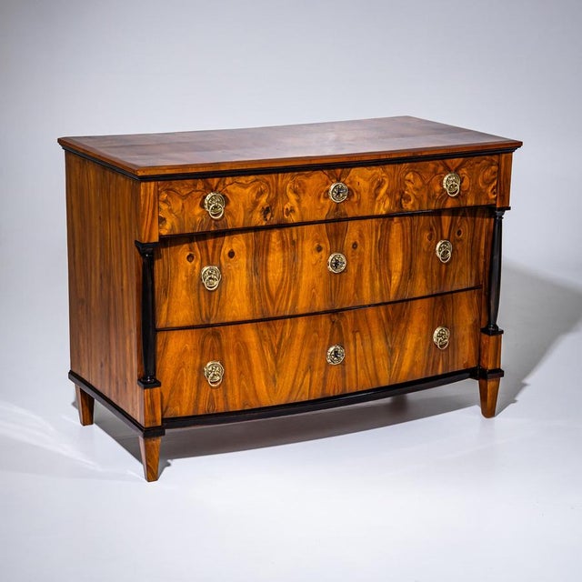 Large Biedermeier chest of drawers featuring three drawers and a subtly bombé lower front. The top drawer is supported by...