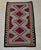 Southwestern-style handwoven wool rug featuring a striking geometric design in rich burgundy red, warm taupe gray, camel...