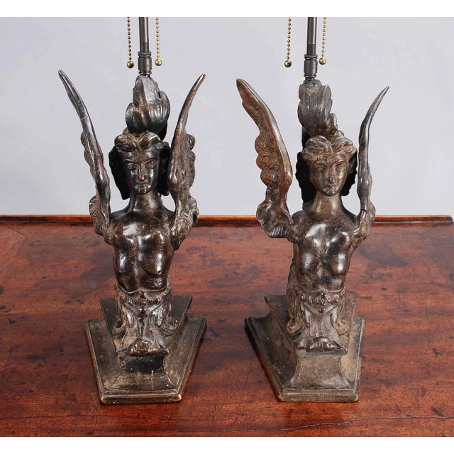 A pair of bronze sculptures which have been fitted for use as lamps. Each sculpture depicts a mythical creature with the...