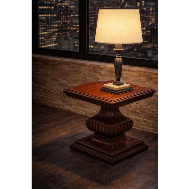 Elegant square pedestal side table crafted from solid wood, featuring a sculptural carved base and finished in Old Chapel...