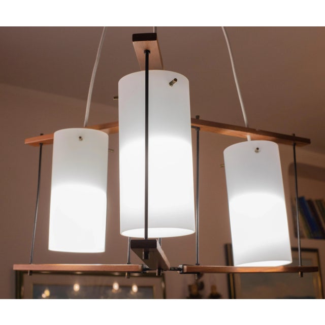 Mid-century Italian chandelier made of polished brass, wood and opaline glass, attributed to Stilnovo The restoration was...