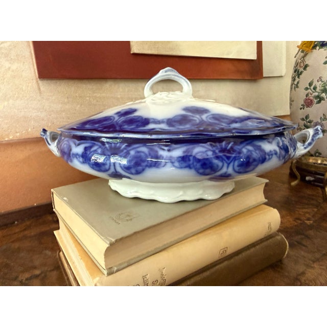 A beautiful antique English flow blue covered tureen featuring richly saturated cobalt blue floral scrollwork that softly...