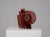 A striking abstract glass sculpture composed of strong geometric forms and flowing curves. The deep red-brown transparent...