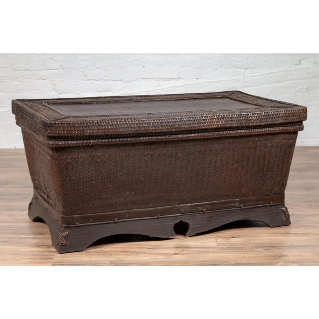 A Chinese antique basket coffee table from the early 20th century, made of dark brown woven rattan over wood. Born in...