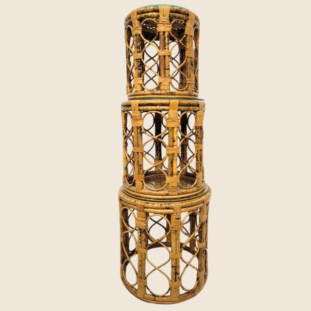 A chic set of three mid-century bamboo nesting tables with woven cane tops and open rattan lattice sides. Perfect as side...