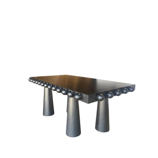 The architectural Dot Dining Table; features a wood frame and ball design all around the edge of the tabletop, making it...