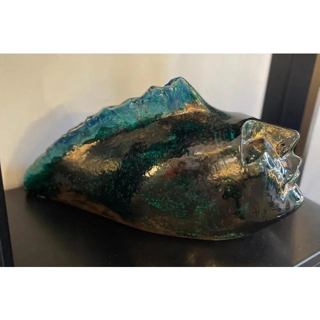 Sculpture depicting a head, crafted in glazed ceramic with shades ranging from black to green. A 1960s work. Measurements:...