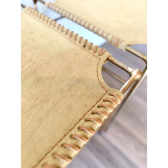 Pair of sculptural brass and animal hide accent benches featuring hand-laced hide and leather seats and slender brass-...