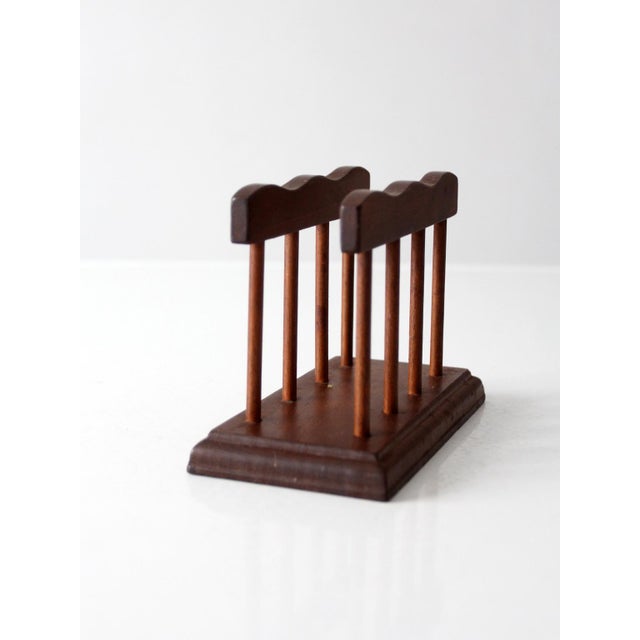 Mid-century wood holder with sculpted rails, turned dowel supports, and a rich walnut-toned finish. A warm, functional...