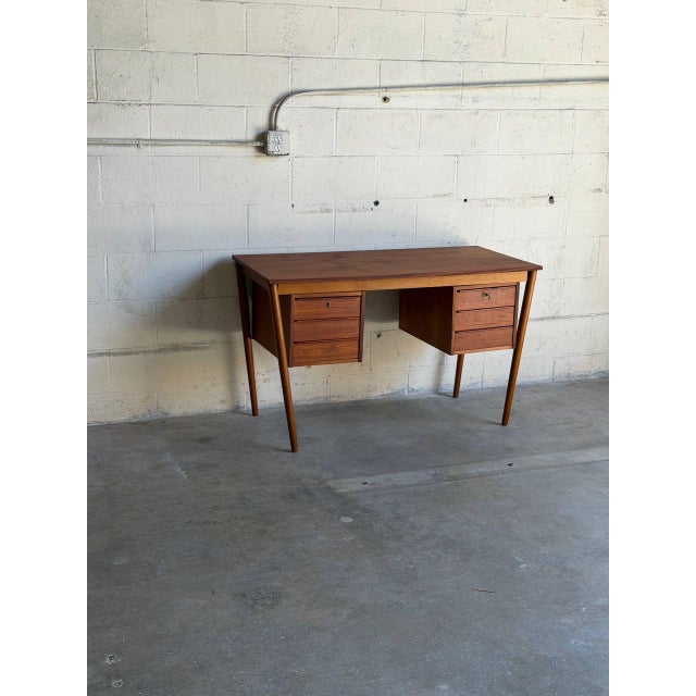 Beautiful vintage Danish Mid-Century Modern writing desk crafted in warm teak with elegant tapered round legs and clean...