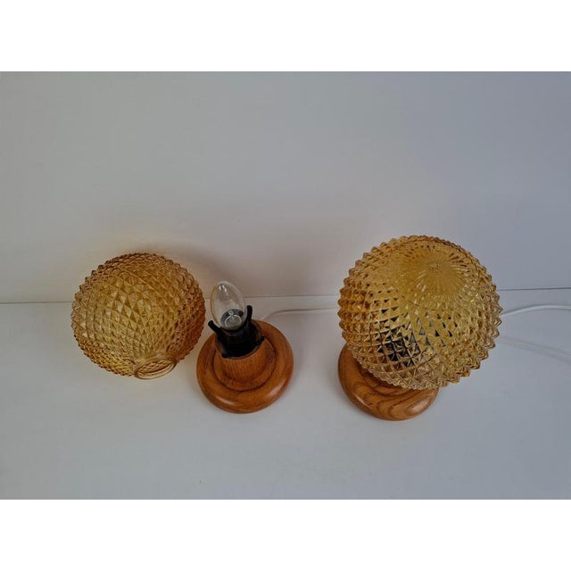 A charming pair of mid-century modern table lamps from czechoslovakia, made with textured amber pressed glass shades and...