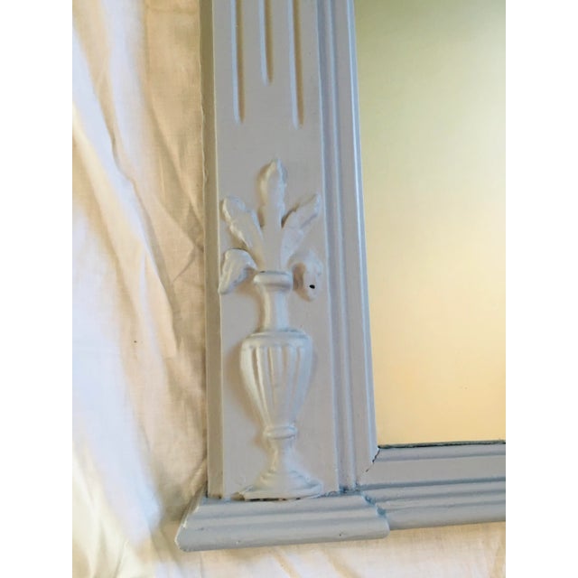 This painted wooden mirror is in neoclassical style The central urn has a fleur d’lis roping it and swags of flowers left...